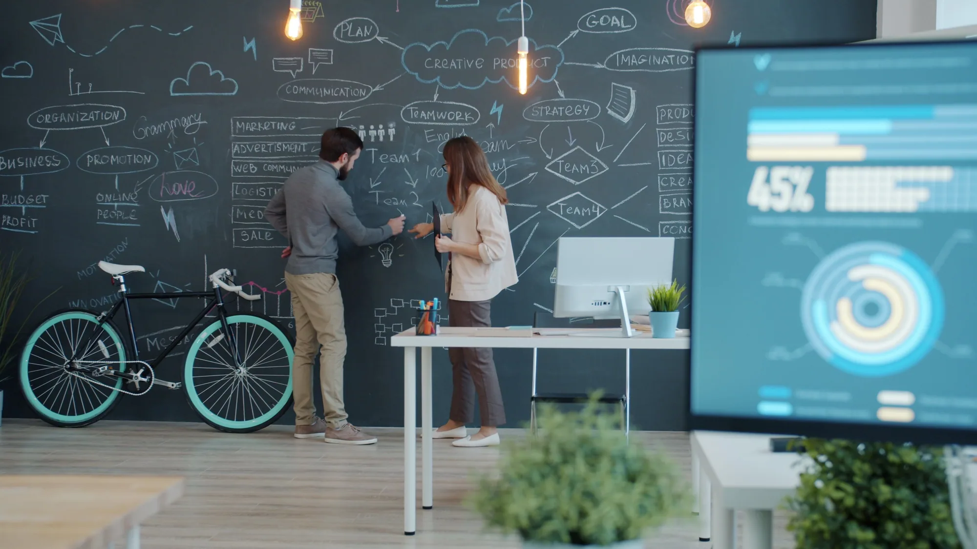 Two colleagues developing ideas at a studio chalkboard